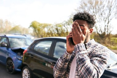 Trafik kazasından sonra hasar görmüş bir arabanın yanında duran genç adam cep telefonu kullanan sigorta şirketine olay bildirdi.