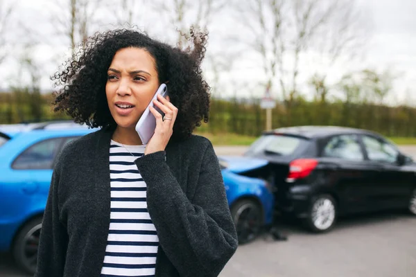 交通事故後の被害車のそばに立つ若い女性携帯電話を使用して保険会社に事故を報告 — ストック写真