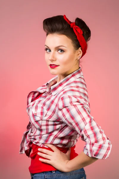 Hermosa mujer joven con pin-up maquillaje y peinado posando sobre fondo rosa — Foto de Stock