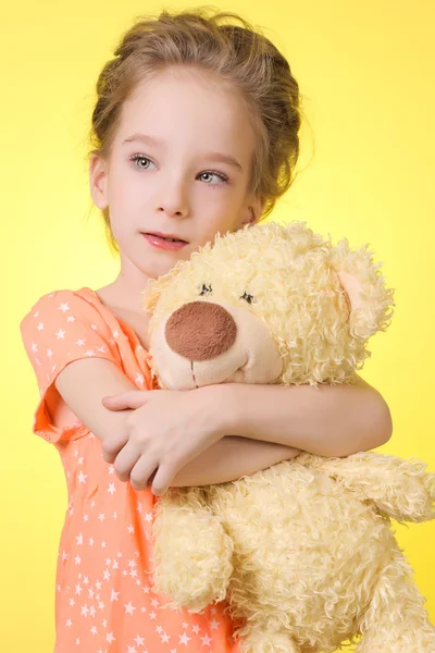 Retrato de menina bonita 6 anos que abraça um urso de pelúcia isolado no fundo amarelo — Fotografia de Stock