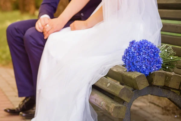 Bride and groom sitting on a bench — Stock Photo, Image