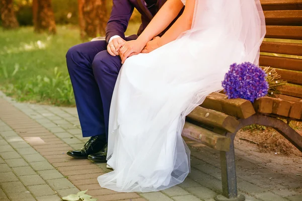 Bride and groom sitting on a bench — Stock Photo, Image