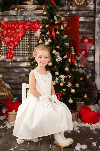 Bonito menina bonita jovem em vestido de Natal branco está sentado em — Fotografia de Stock
