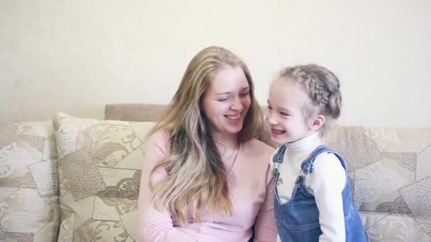 Petite fille embrasse mère joue, vue rapprochée sur le canapé — Video