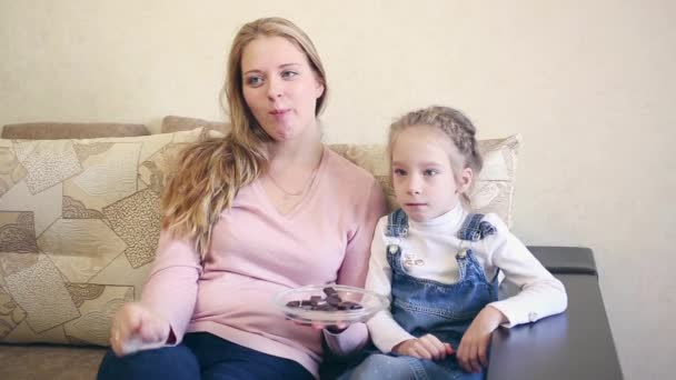 母亲和女儿吃巧克力和看电视 — 图库视频影像