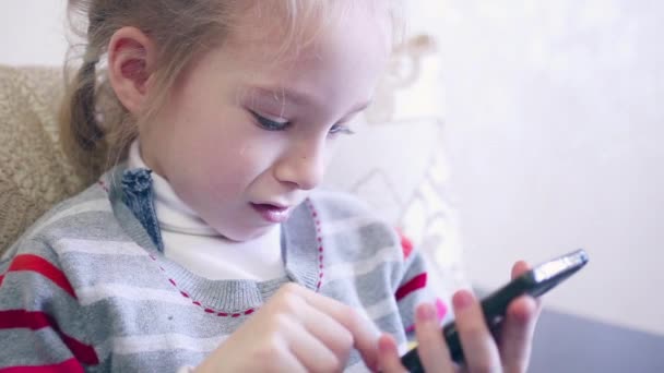 Gros portrait d'enfant. Fille à l'aide de téléphone mobile et sourire . — Video