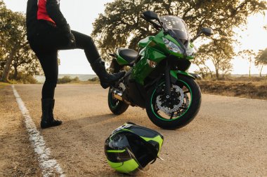 Kafası karışmış ve sinirli bir motosikletlinin önü yolda bozuk motosikletiyle ve kaskı asfaltta yatıyordu. Yardım ve tamirci bekleniyor.