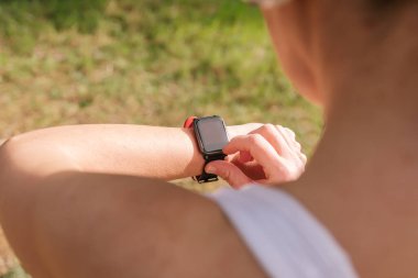 Giyilebilir teknoloji spor aletleri, kulaklık ve akıllı saatle müzik dinlemek için telefonu kullanan İspanyol bir kıza yakışıyor. Fitness Panorama Teknolojisi. Etkin yaşam biçimi.