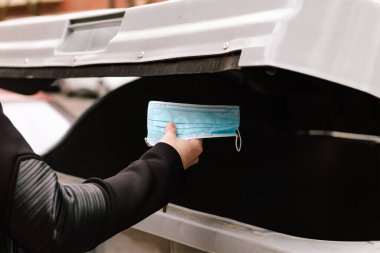 Kullanılmış tıbbi maskeyi çöp kutusuna atan bir adamın eli. Çovid 'le geri dönüşüm yapmak için. çevre günü kavramı