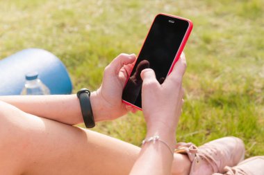 Mobil uygulamayı kullanan bir bayan sporcunun elleri günlük açık hava eğitimini takip cihazıyla yapıyor. Boşluğu kopyala.