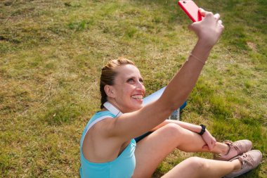 Sporcu kadın sıkı bir çalışmadan sonra sosyal medya profili için selfie çekiyor. Spor, teknoloji ve yaşam tarzı kavramı