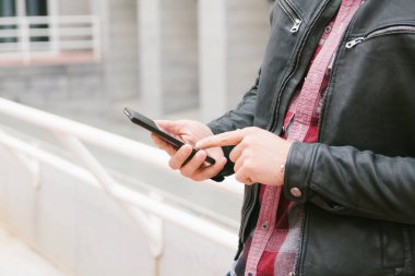 Sokakta cep telefonu ya da akıllı telefon kullanan birinin elleri. Kopyalama alanı ile