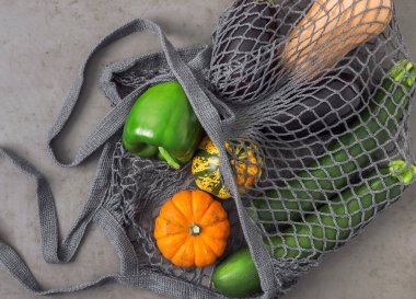 Sonbahar sebzeleri pamuk bir örgü içinde gri taştan bir zemin üzerinde uzanır..