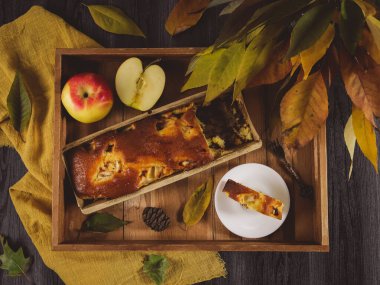 Elmalı Charlotte, ahşap bir tepside, sonbahar yapraklı bir buket, yakın plan..