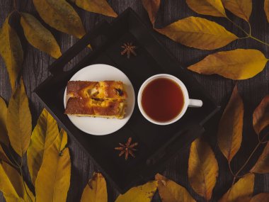 Charlotte ve çay, sonbahar yapraklı bir masanın üstünde, yakın çekim manzaralı. .