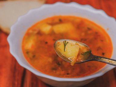 Bir kaşıkta bezelye çorbası, arka planda tabak ve ekmek kırmızı arka planda, yakın planda, üst tarafta yatar..