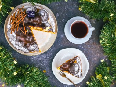 Profiterollü çikolatalı pasta, dilimlenmiş pasta, koyu arkaplanda noel dekorasyonu ve kahve, yakın plan üst görüntü..