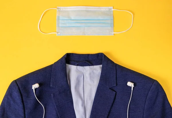 jacket, headphones and a medical mask lie on a yellow background, a close-up top view