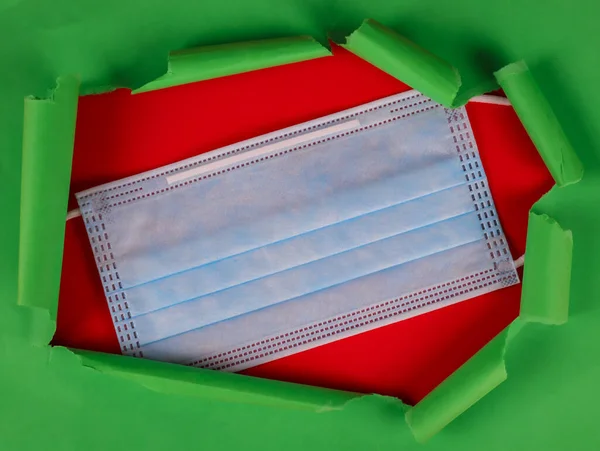 Медична Маска Лежить Посередині Червоному Тлі Зверху Зеленим Рваним Папером — стокове фото