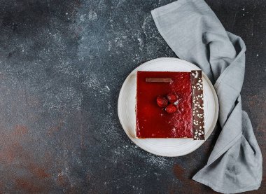 Bir tabakta çilekli pasta ve sağda bir peçete. Koyu gri bir zemin üzerinde uzanıyor. Solda yazı için bir yer var..