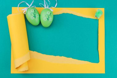 Sarı yırtık kağıt çerçeveli Paskalya yumurtası ve tavuk. Yeşil arka planda metnin için yer var. Yakın plan..