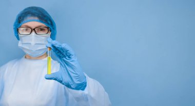 Bir doktor, solunda sarı bir aşı bulunan bir test tüpünü solunda mavi bir arkaplan, solunda yazı için boşluk olan, yakın plan görüntüsü olan bir test tüpü tutuyor..