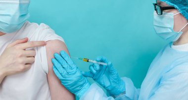 Doktor bir hastayı kolundan aşılar, yakından bakar..