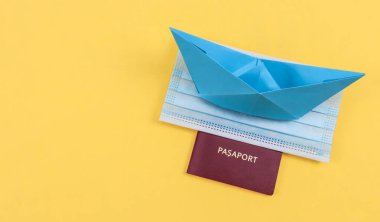 Pasaport, maske ve origami düzlemi sağda sarı bir zemin üzerinde solda metin için boşluk, yakın plan yan görünüm.