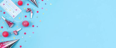 Maske ve konfeti ile renkli doğum günü seti sol tarafta mavi bir zemin üzerinde uzanır metin için sağda, üst yakın çekim.