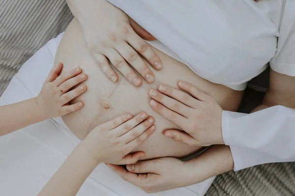 Mãos Bebê Seguram Barriga Uma Mãe Grávida Deitada Cama Vista — Fotografia de Stock