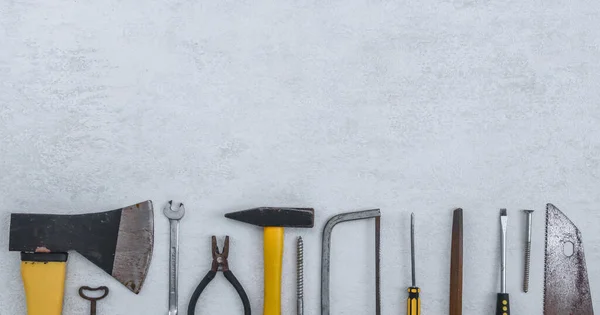 Set of old construction tools on a concrete background with space for text on top, flat lay close-up.