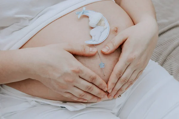 一个怀孕的女人在腹部以心脏的形式握住她的手 这是一个近距离的侧视 — 图库照片