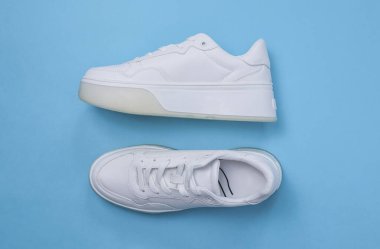 Beyaz spor ayakkabılar mavi arka planda, yakın planda yatar..