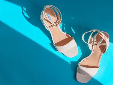 Bir çift beyaz sandalet sağ tarafta açık mavi bir arkaplanda uzanıyor metin için yer var, üst görünüm yakın plan.