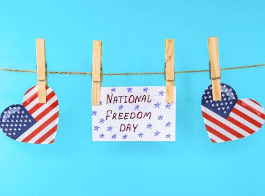 Amerikan bayrağı taşıyan kalpler ve üzerinde yazı olan bir yaprak: Ulusal Özgürlük Günü, çamaşır ipinde asılı, yakın plan yan görüş.