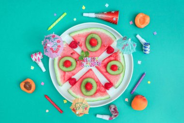 Meyveli karpuzlu sandviç ve yeşil arka planda doğum günü süslemesi..