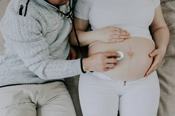 Pai Escuta Com Estetoscópio Batimento Cardíaco Bebê Uma Mãe Grávida — Fotografia de Stock