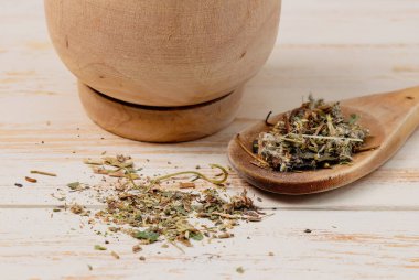 Ahşap kaşıkta kurutulmuş çay ve masada duran havan topları için faydalı bir bitki koleksiyonu. Beden terapisi konsepti.