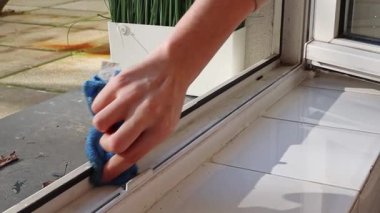 Tanınmayan beyaz bir adam, lastik profili yapıştırmadan önce kirli iç pencere çerçevelerini mavi mikrofiber kumaşla yıkıyor. Yan görüntüyü yavaş çekimle çok yakından çekiyor. Pencere çerçevelerinin onarımı, yıkanması ve yalıtımı, ilkbahar işi.