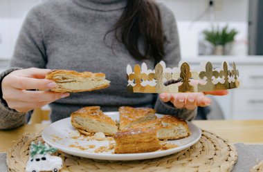 Masada oturan, elinde bir parça kraliyet bisküvisi ve altın bir taç tutan beyaz bir kızın portresi. Konsept: tatil zamanı, kraliyet bisküvisi yeme zamanı.