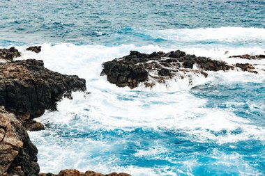 Bulutlu bir sonbahar gününde Atlantik Okyanusu 'nun kuzey kıyısındaki volkanik kayalara nazikçe çarpan sakin okyanus dalgalarının güzel yatay görüntüsü. Kavram: güzel doğal altyapılar ve duvar kağıtları.
