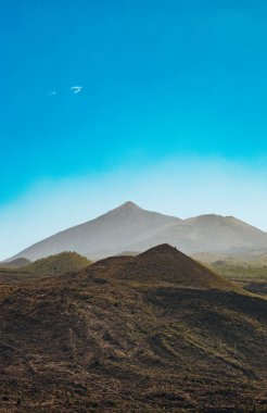 Güneşli bir sonbahar gününde Tenerife Adası 'nın arka planında Teide Dağı' nın olduğu tepelik manzaranın güzel dikey görüntüsü. Kavram: doğal arka plan, dağ manzarası ve yollar.