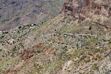 Güneşli bir sonbahar gününde, Tenerife adasındaki volkanik bir dağın tepesinde, yukarıdan yakın bir görüntü olan, yılanımsı asfalt bir yolun yatay görüntüsü. Kavram: doğal arka plan, dağ manzaraları ve yollar.
