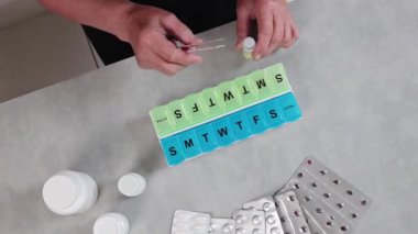 Yaşlı, tanınmayan bir kadın avucunun içine sarı haplar döker ve gündüzleri bir masada otururken onları bir hücre deposuna koyar, yukarıdan yavaş çekimle yakın çekimde. İlaç almak için kavram süresi