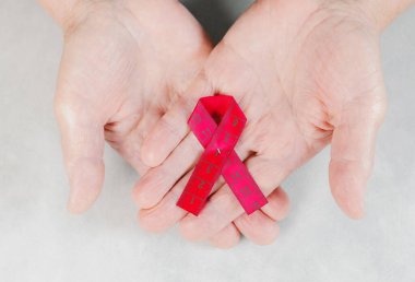 Döngü şeklinde küçük bir kırmızı mezura, yukarıdan yakından görünen, yaşlı, beyaz bir kadının avuçlarında yatar. Dünya AIDS Günü kavramı, umudun sembolü..