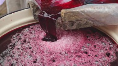 Yağmurlu bir sonbahar gününde arka bahçede, koyu kırmızı, taze sıkılmış üzüm suyu damlatan tek bir diş minesi saksısı, yan görüş, yavaş çekim. Konsept: Geleneksel yerel şarap yapımı, retro teknoloji, ev yapımı.