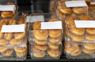 Mağazadaki tezgahın üzerinde duran şeffaf plastik kutuların içinde taze pişmiş tatlı çöreklerin güzel manzarası, yakın çekim. Zaman kavramı tatlı hamur işleri, taze çörekler.