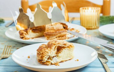 İçinde bir sürpriz bulunan, kraliyet galetesinin kesilmiş bir parçası, güzel dekore edilmiş mavi ahşap bir masanın üzerinde, tarlanın derinliğine sahip yakın plan manzaralı bir tabakta yatıyor. Kavram: şenlikli yemek, Fransız kültürü.