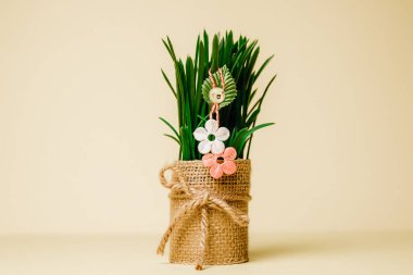 İki çiçeğin güzel el yapımı martisti, bir taç yaprağı ve bir buğday filizinin üzerinde sallanan neşeli gülen bir yüz kenar tarafında fotokopi alanı olan pastel sarısı bir arka planda duruyor..