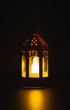 Bir yaldızlı küçük Fas kulesi feneri. Gece vakti, üzerinde LED mum ve alevin yansıması olan. Yakın plan. Şenlikli dekor konsepti, Ramazan Kareem.
